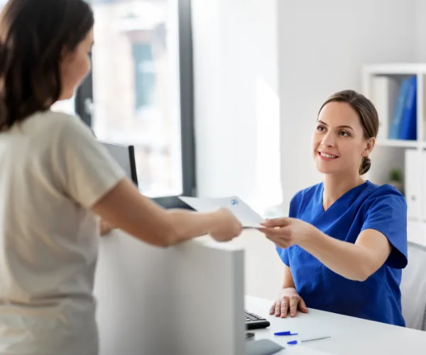 Assistante dentaire et dentiste accueillant un patient à l'accueil du cabinet